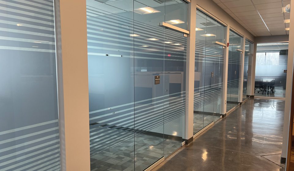 A hallway with glass walls and concrete floors.